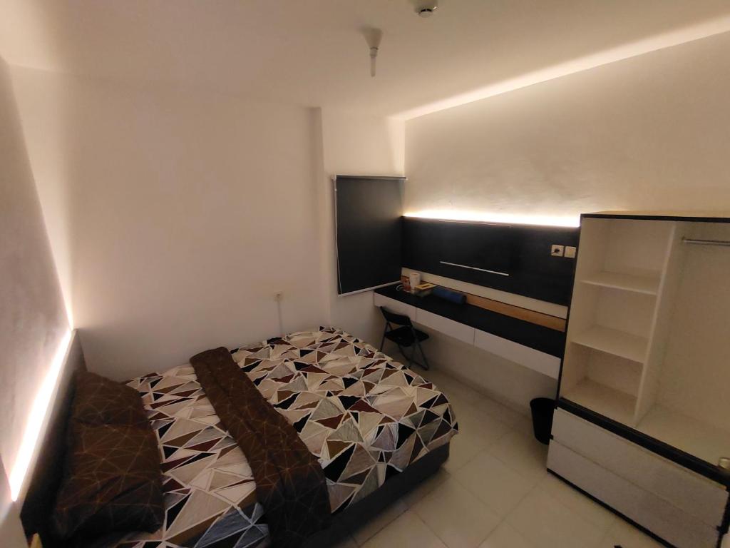 a small bedroom with a bed and a television at RDTROOM At Aeropolis in Teko