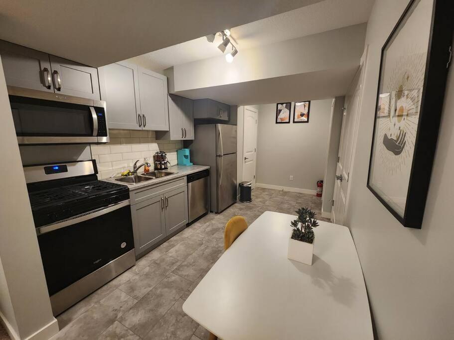 een keuken met een witte tafel en een fornuis top oven bij Deluxe 2 bedroom suite with*Netflix/Cable/Prime in Edmonton