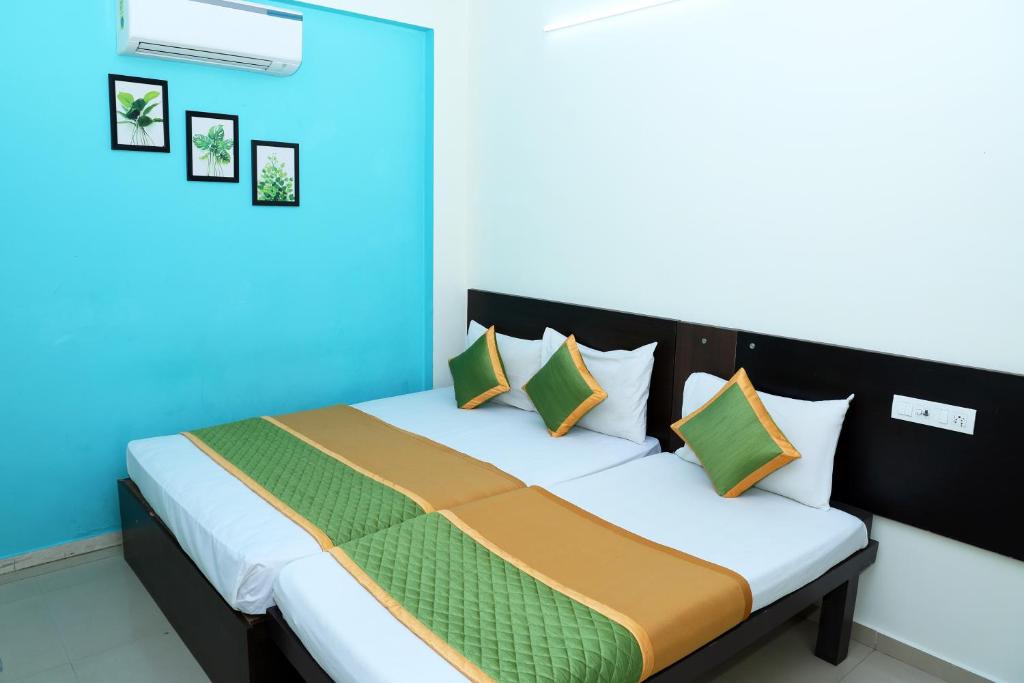 a bedroom with a bed with blue and green pillows at Royal Green - Airport Stay in Chennai