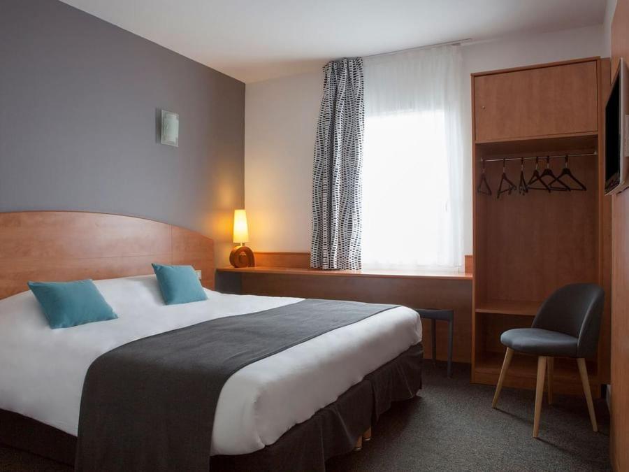 a hotel room with a large bed and a window at The Originals City, Plume Hôtel, Bressuire (Inter-Hotel) in Bressuire