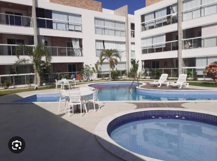 a swimming pool with a table and chairs next to a building at Apartamento na Praia do Francês in Marechal Deodoro
