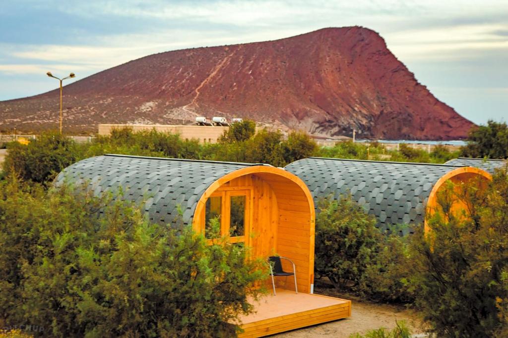 a couple of small houses in a field with a mountain at Camping Montaña Roja in El Médano