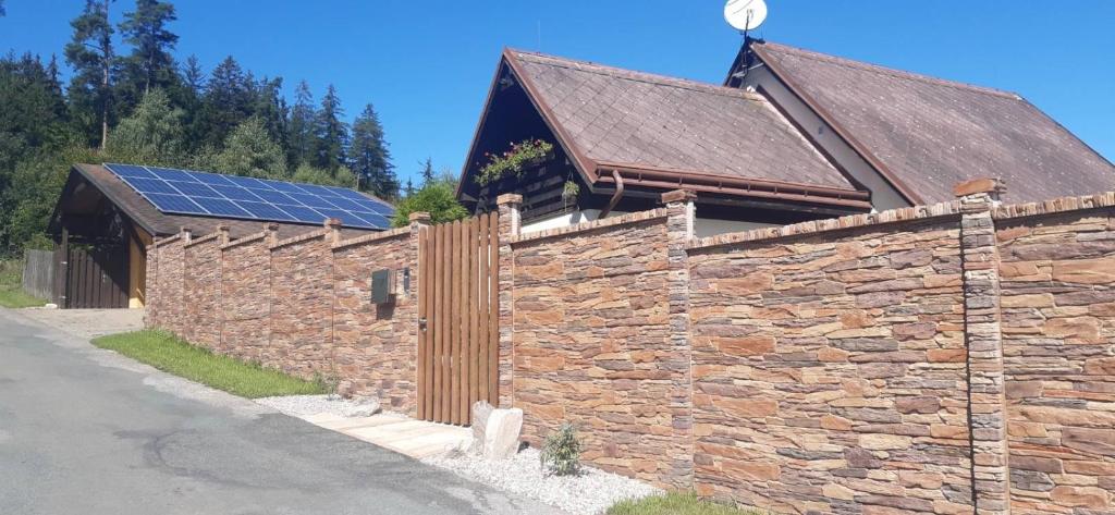 a stone wall with a building with solar panels on it at Apartman Daniela in Radvanice