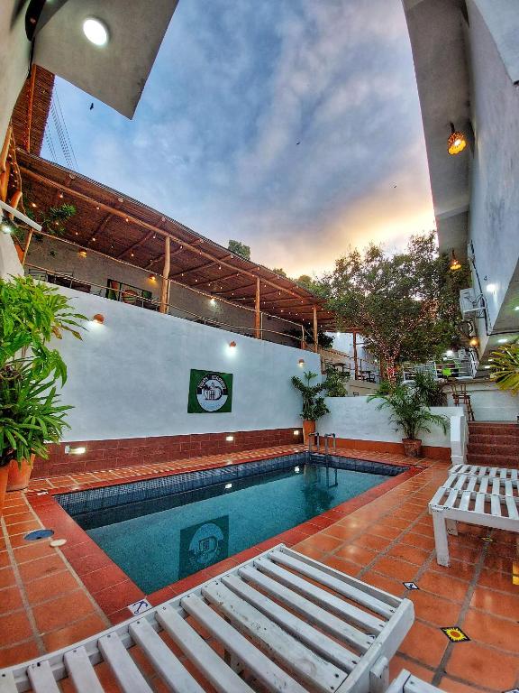 a swimming pool with two white benches next to it at Posada Restaurant La Guaricha in Catia La Mar