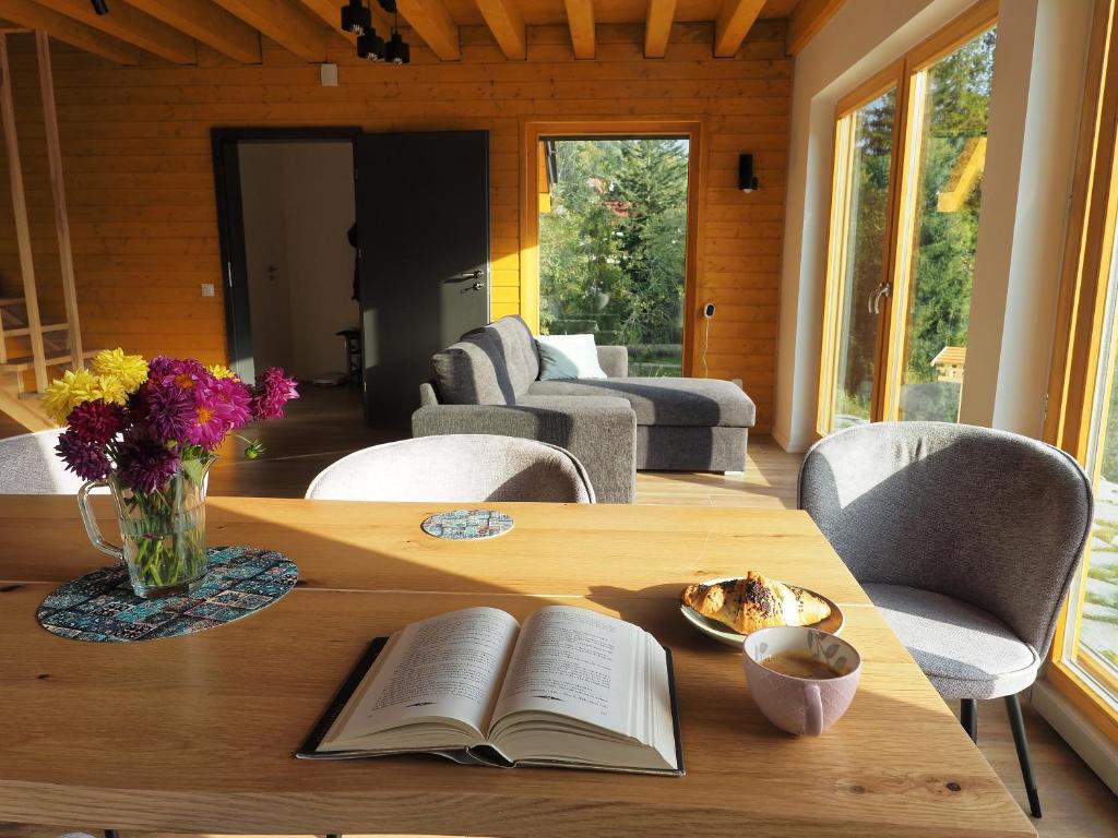 einen Holztisch mit einem offenen Buch und einer Vase aus Blumen in der Unterkunft HillOut - Dom w Milówce - Workation - Praca zdalna in Milówka