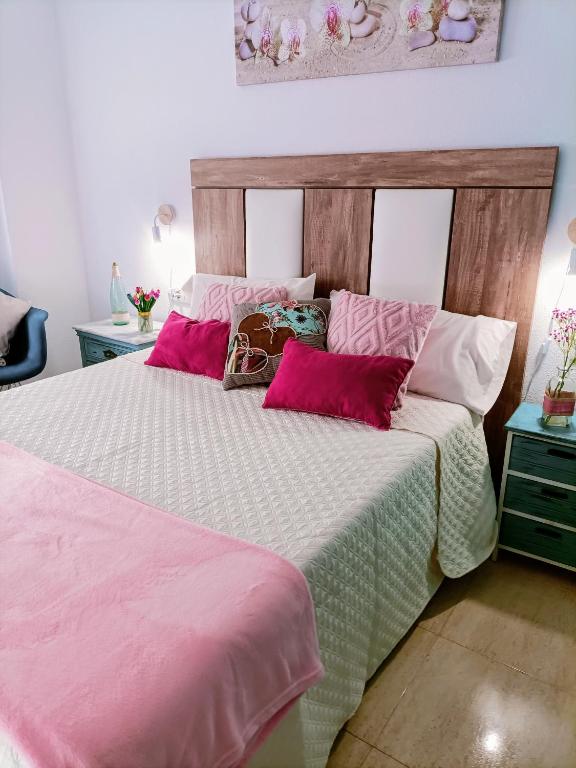a bedroom with a large bed with pink and white sheets at Apartamentos Hondahouse Mar Menor, 1 o 2 dormitorios in Cartagena