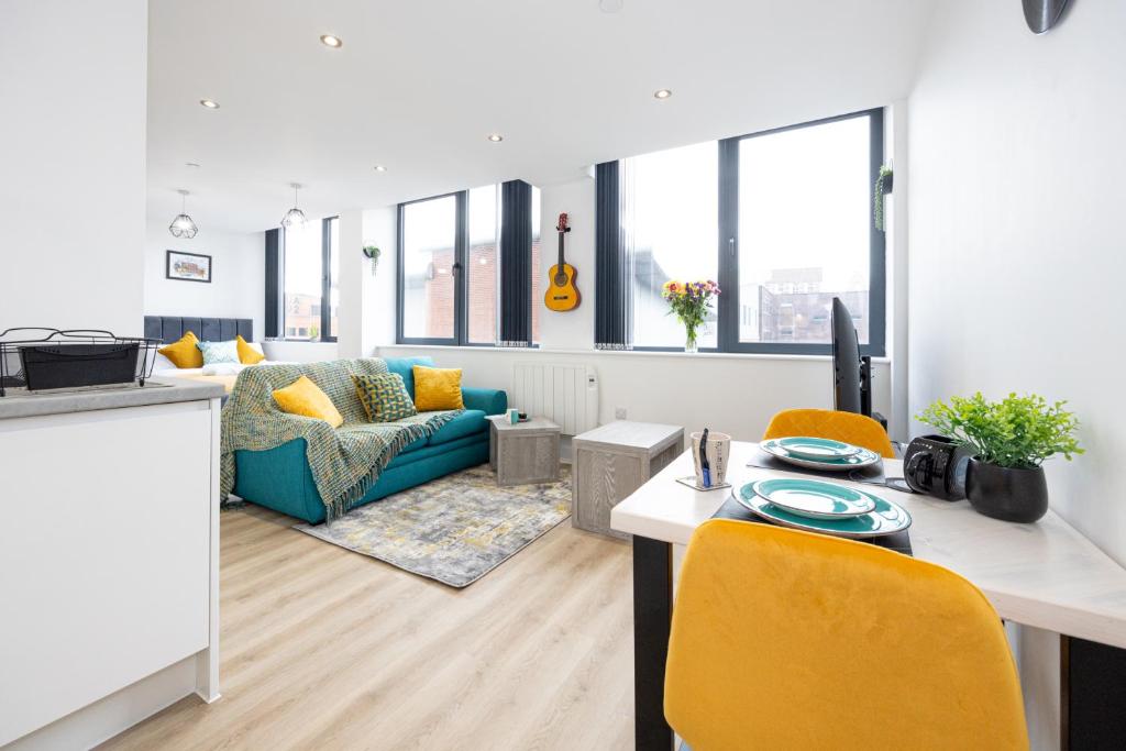 a kitchen and living room with a table and yellow chairs at Bright Stylish Studio Apartment in Old Trafford in Manchester