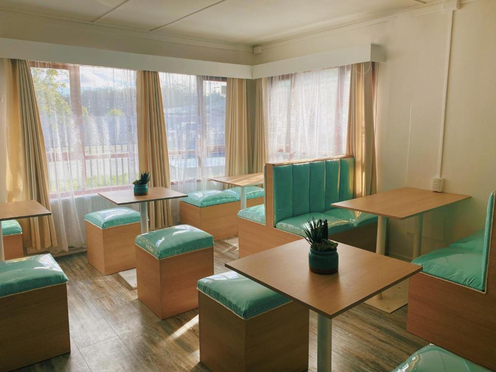 un restaurante con sillas y mesas verdes y una ventana en Indomito Sur Hostel, en Punta Arenas