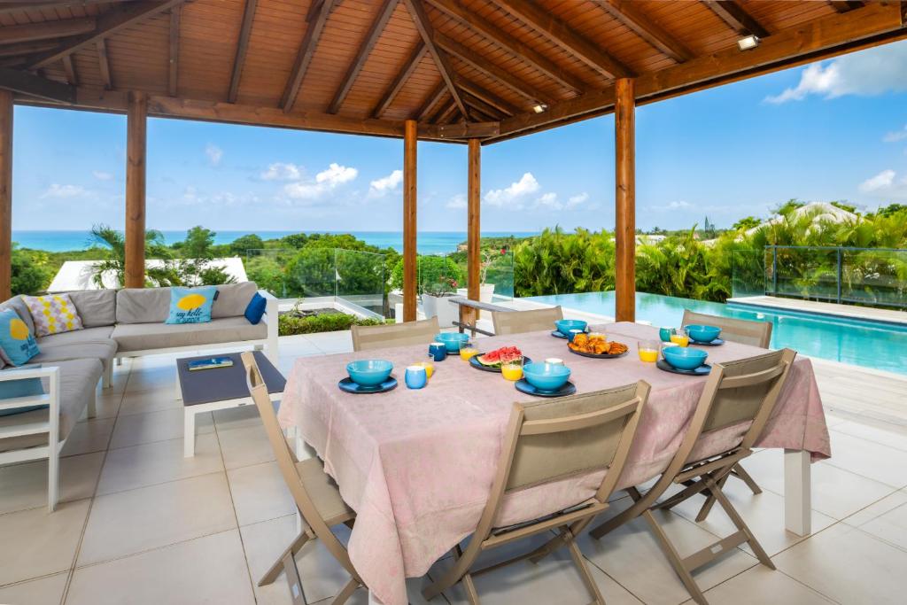 a dining room with a table and chairs and a pool at La Villa KAZ DEL MAR in Sainte-Anne