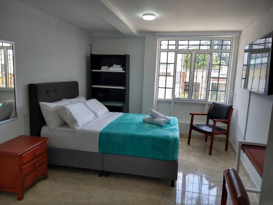 - une chambre avec un lit, une chaise et des fenêtres dans l'établissement Apartamento acogedor confortable y céntrico para 2, à Armenia