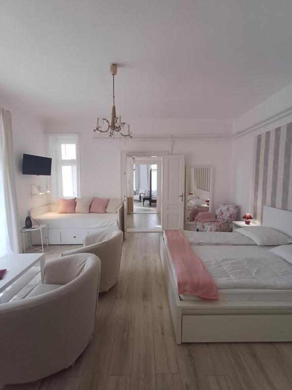 ハイドゥーナーナーシュにあるTornácos Vendégházのベッド2台とソファが備わる広い白い客室です。