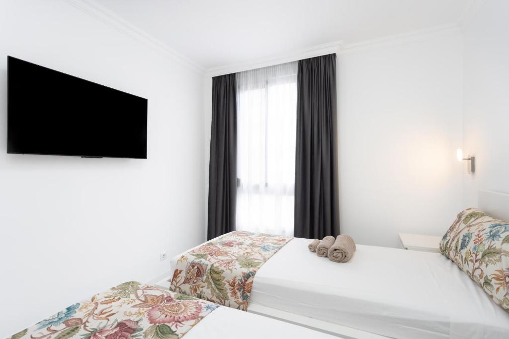 a white bedroom with a bed and a tv at Apartamento Clara in Los Cristianos