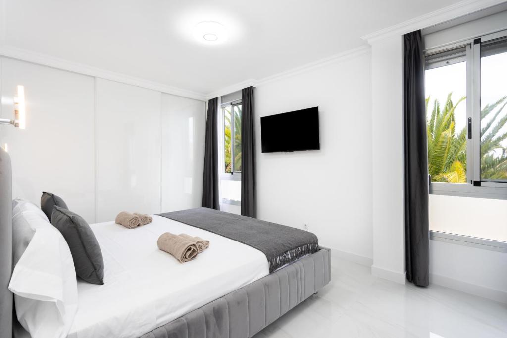 a white bedroom with a bed and a tv at Apartamento Clara in Los Cristianos