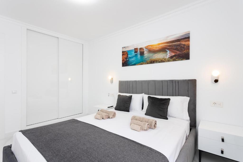 a bedroom with a white bed with a painting on the wall at Apartamento Clara in Los Cristianos