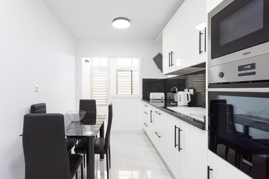 a white kitchen with a table and a dining room at Apartamento Clara in Los Cristianos