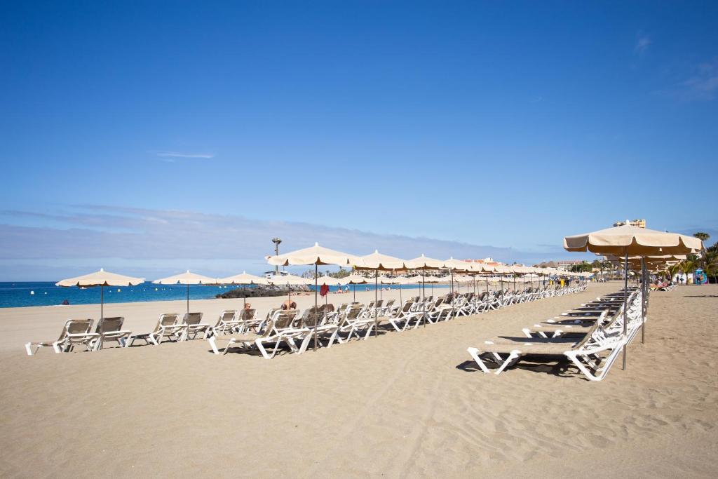 a row of chairs and umbrellas on a beach at Apartamento Clara in Los Cristianos