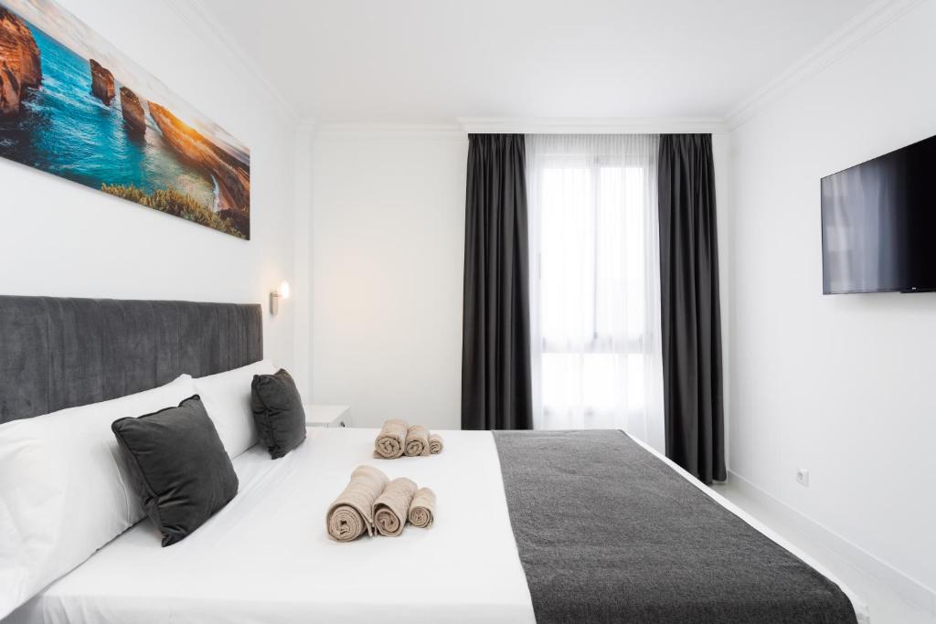 a bedroom with a white bed with slippers on it at Apartamento Clara in Los Cristianos