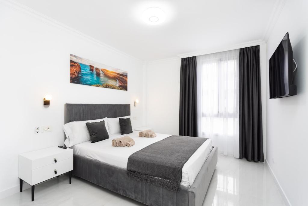 a white bedroom with a large bed and a window at Apartamento Clara in Los Cristianos