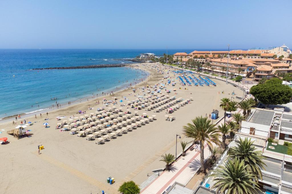 a beach with umbrellas and people on the beach at Apartamento Clara in Los Cristianos