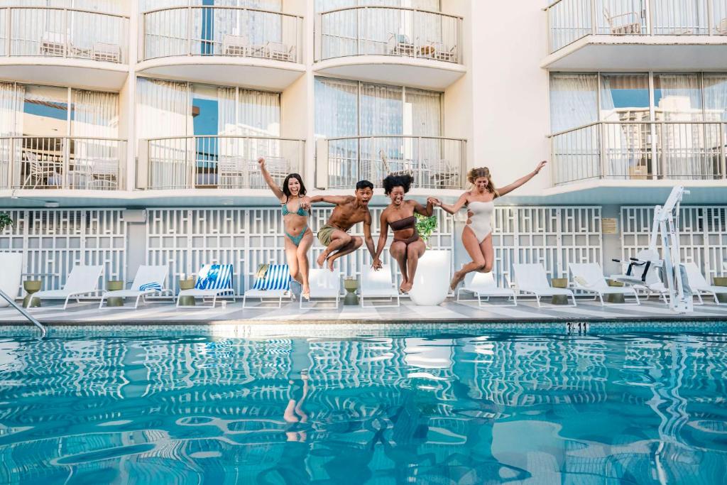 un groupe de personnes sautant dans une piscine dans l'établissement OHANA Waikiki East by OUTRIGGER, à Honolulu