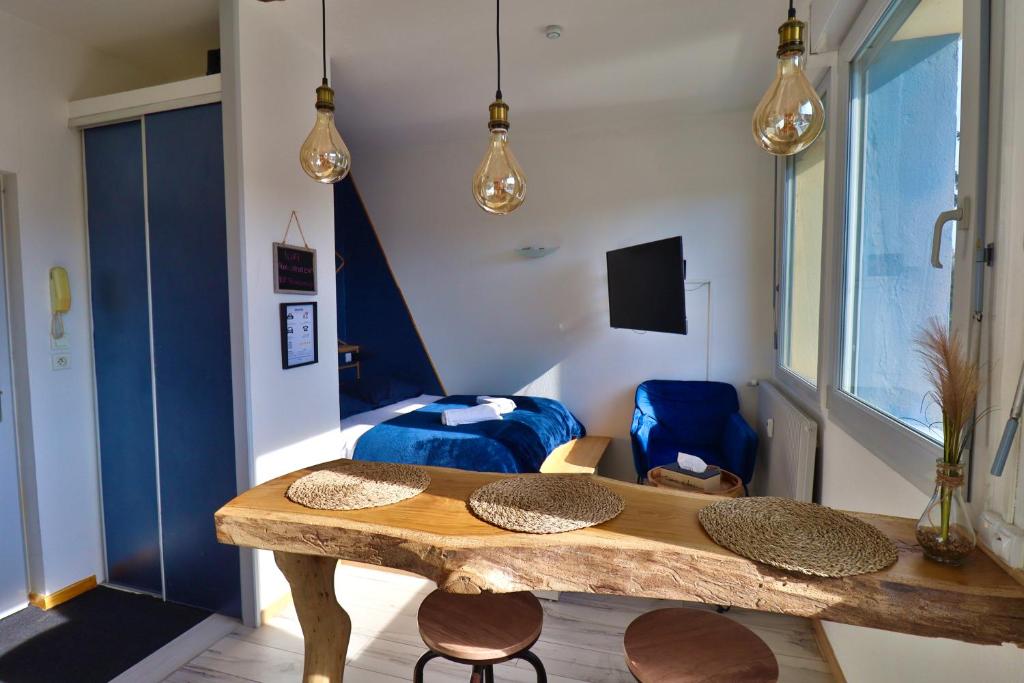 een kamer met een tafel en stoelen en een bed bij Superbe studio cosy et atypique 3 étoiles in Montbéliard