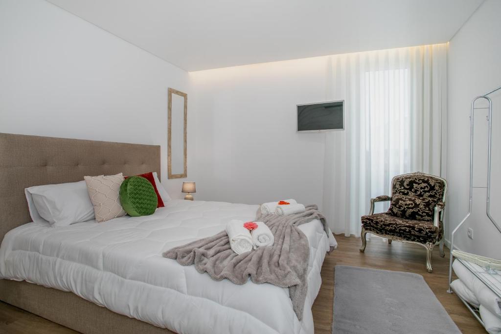 a bedroom with a white bed and a chair at City Glow House in Ponta Delgada