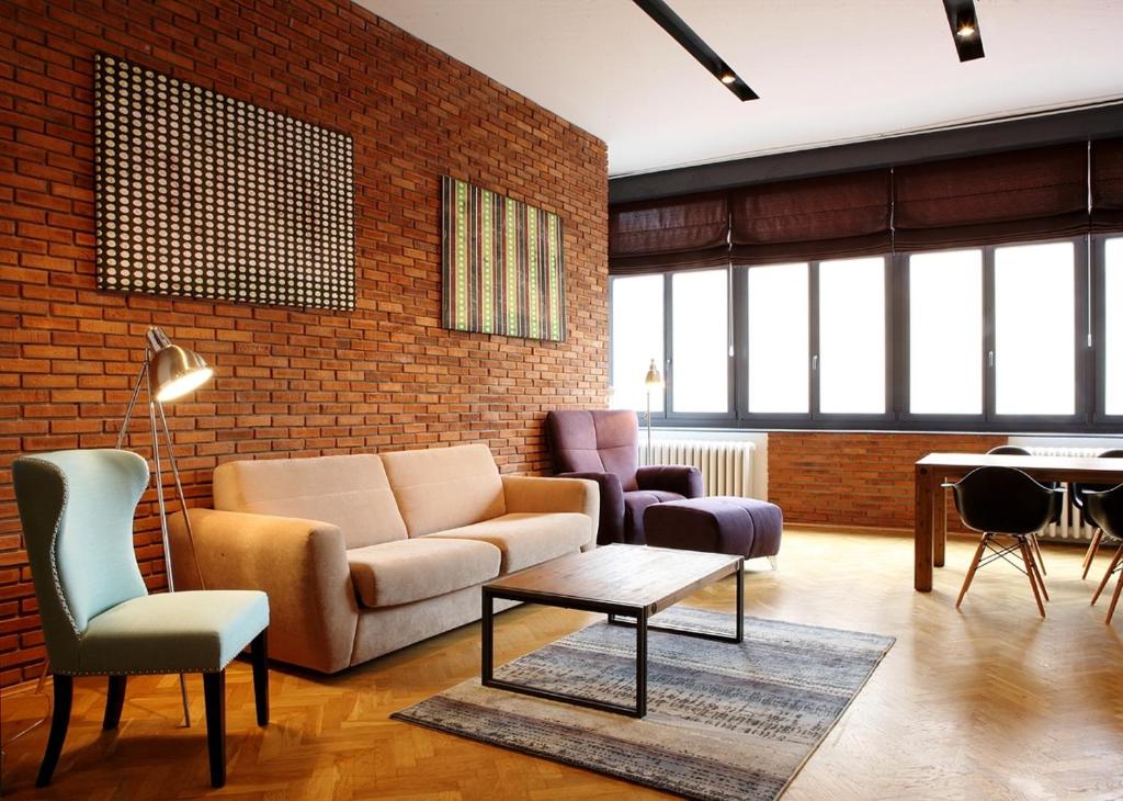 a living room with a couch and chairs and a brick wall at New Design Apartment - Fashion Street in Budapest