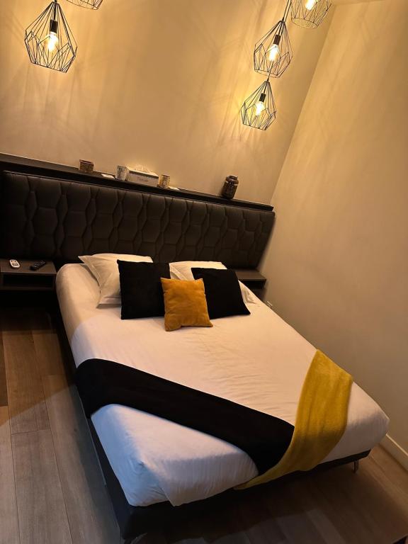 1 dormitorio con 1 cama grande con almohadas negras y amarillas en Love room borabora 3 en Trévoux