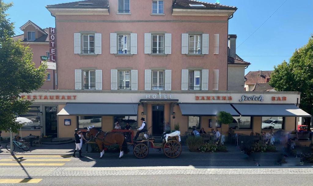 uma carruagem puxada por cavalos em frente a um edifício em Hôtel la Suite em Payerne