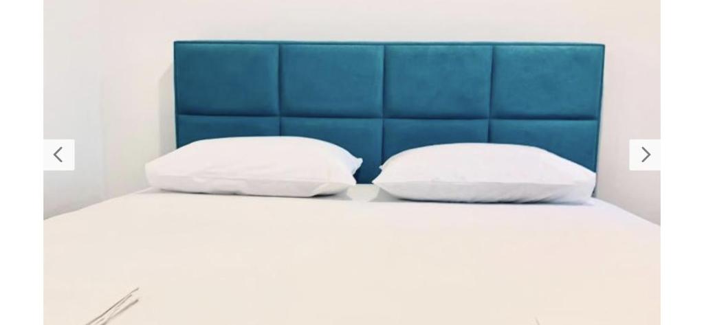 two pillows on a bed with a blue headboard at Monte Star apartments in Budva