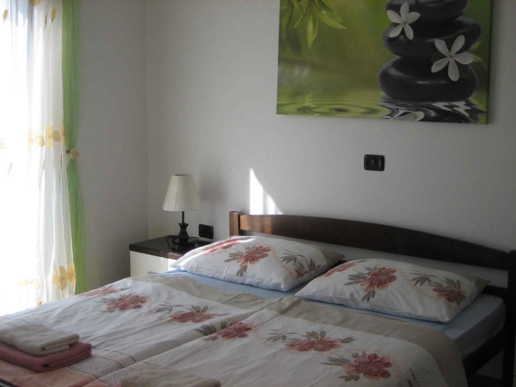 een bed met twee kussens en een schilderij aan de muur bij Apartment in Rogoznica - Sibenik Riviera 36449 in Rogoznica