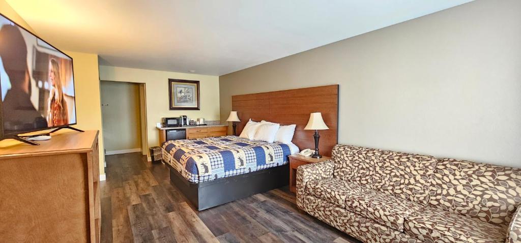 um quarto de hotel com uma cama e um sofá em Mill Village Motel em Eatonville