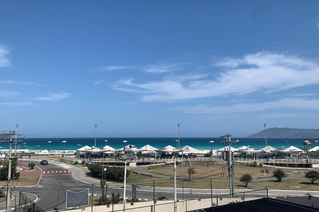 Blick auf einen Strand mit weißen Sonnenschirmen und das Meer in der Unterkunft Espaçoso apê 3 quartos à beira da Praia do Forte com piscina e sauna in Cabo Frio