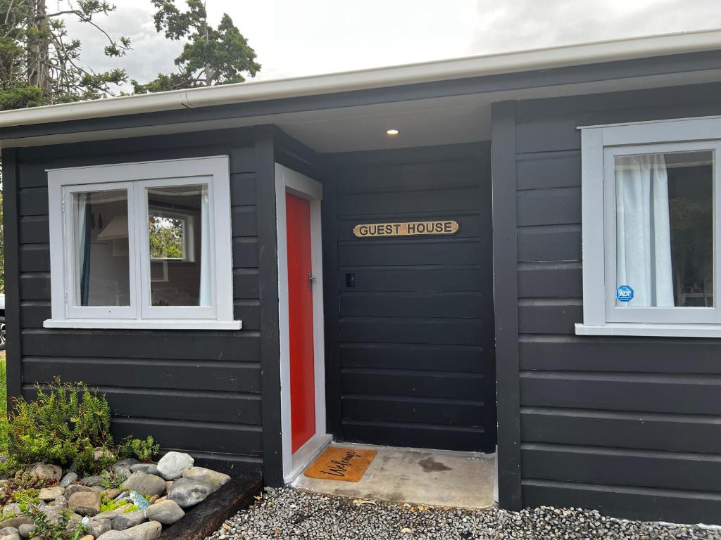 a black shed with a sign that reads guest house at Short Stay- ENTIRE GUESTHOUSE! in Halcombe