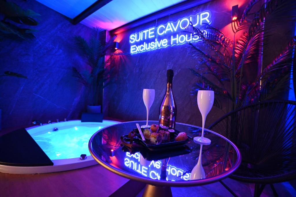Suite Cavour Exclusive House Private Luxury SPA في برينديسي: غرفة مع حوض مع زجاجة من النبيذ وطاولة مع وعاء