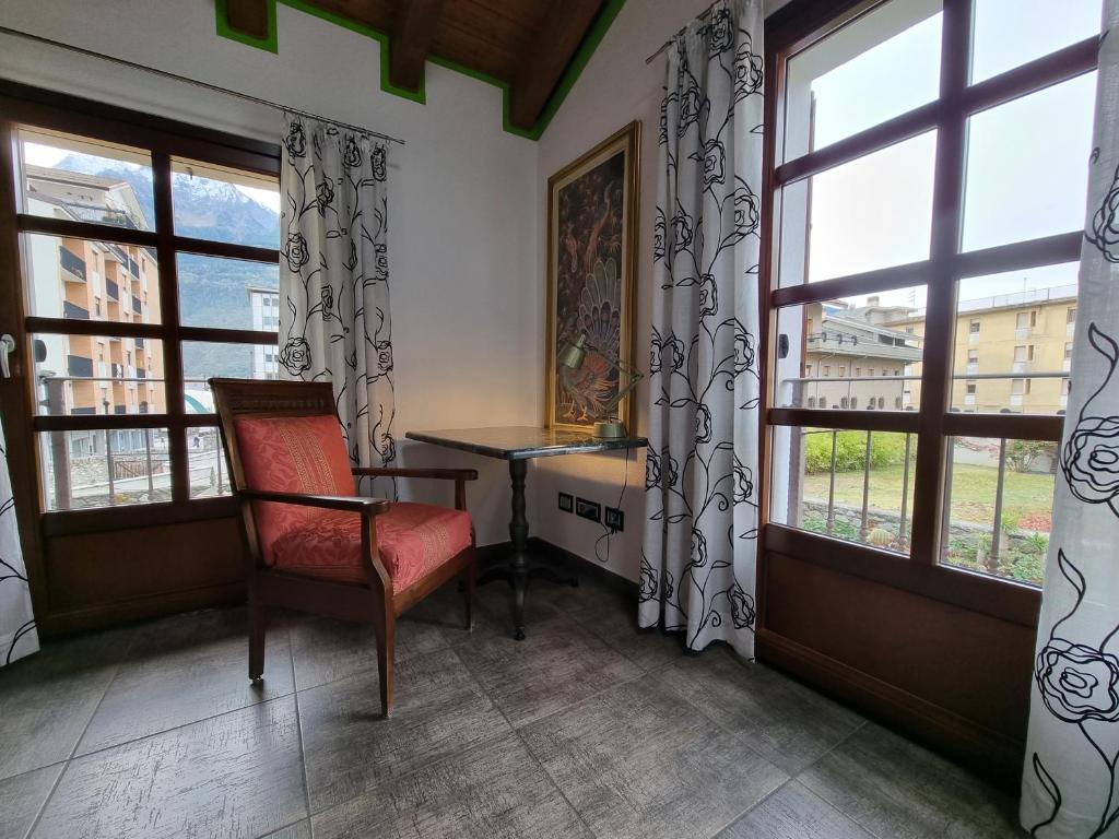 a room with a chair and a table and windows at Maison Bodroz appartamento Charme in Aosta