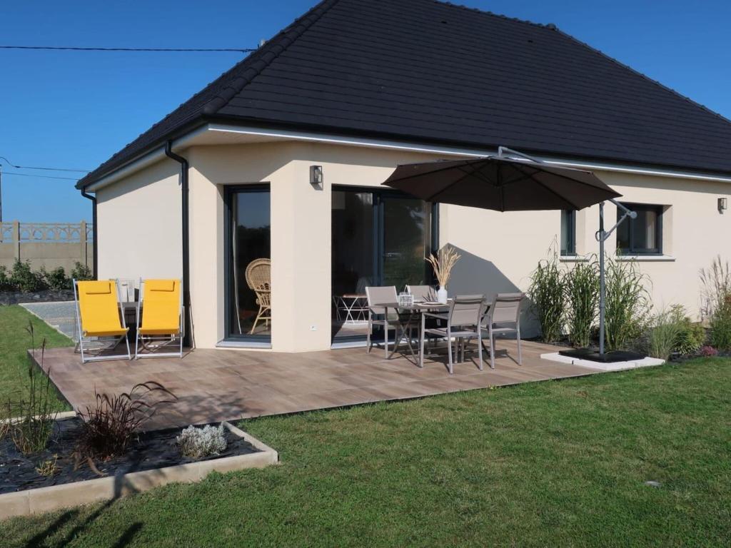 eine Terrasse mit einem Tisch, Stühlen und einem Sonnenschirm in der Unterkunft Charming cottage only 8 minutes from Etretat in Bordeaux-Saint-Clair