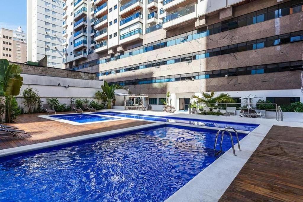 a swimming pool in front of a building at Flat Capitânia Varam 143 Pitangueiras in Guarujá