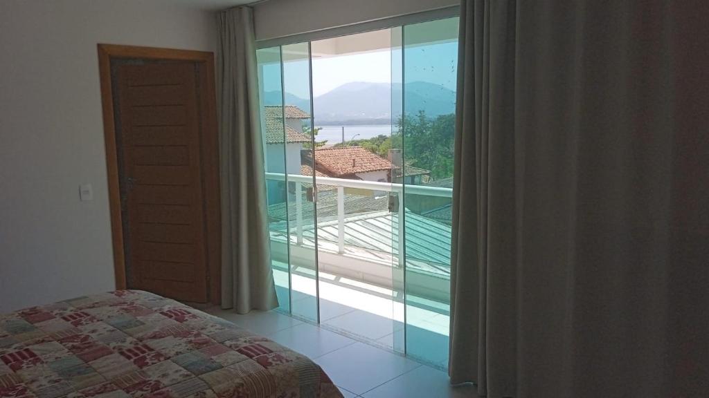 a bedroom with a large window with a view of a balcony at Casa amarela in Niterói