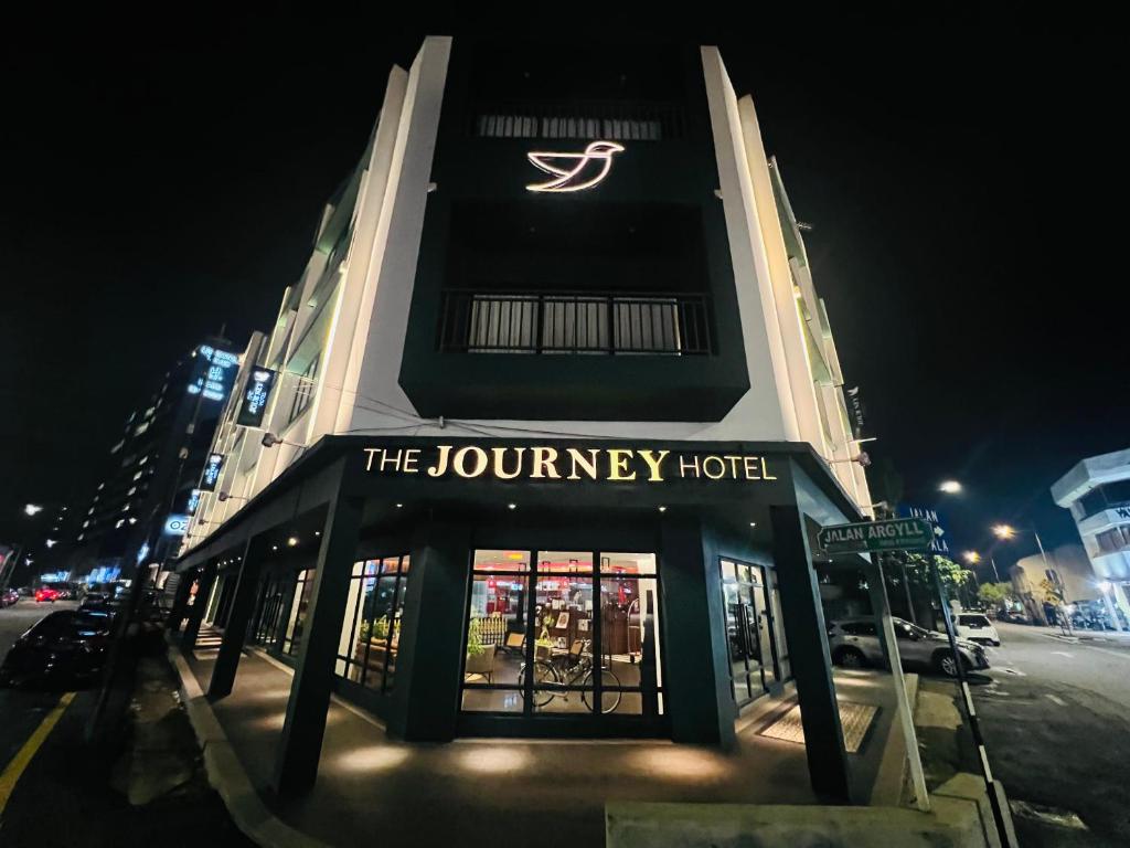 a building with a sign for the journey hotel at night at The Journey hotel in George Town