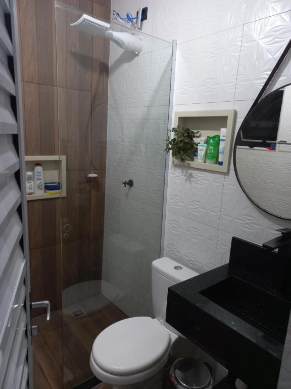 La salle de bains est pourvue de toilettes, d'une douche et d'un lavabo. dans l'établissement Casa mar sol e piscina, à Peruíbe