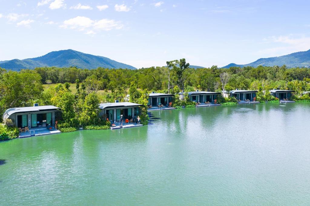 un grand lac avec des maisons et des montagnes en arrière-plan dans l'établissement Samui Fishing Club and Resort, à Na Mueang