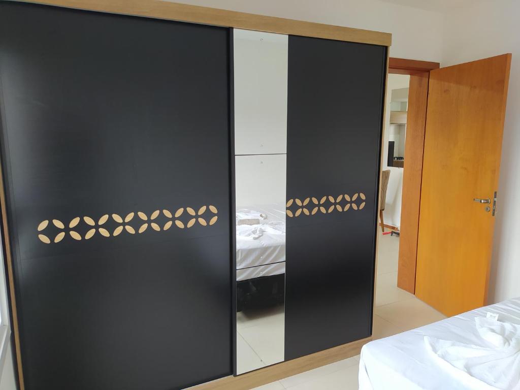 um guarda-roupa preto com um espelho num quarto em Apartamento próximo a gramado, 25km! em Três Coroas