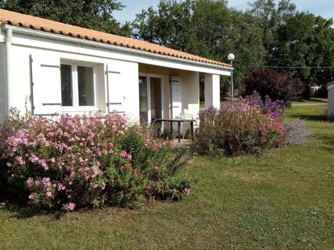 una pequeña casa blanca con flores delante en Holiday complex Le Domaine du Lambon, Prailles-La Couarde - semi-detached house, en Prailles