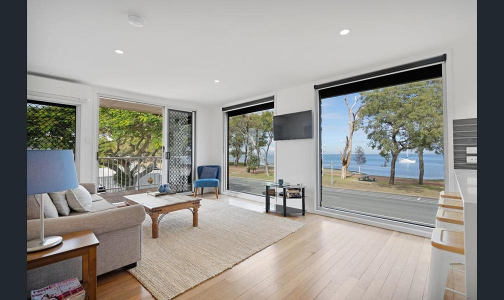 a living room with a couch and large windows at Bribie Waters Apartment in Bongaree