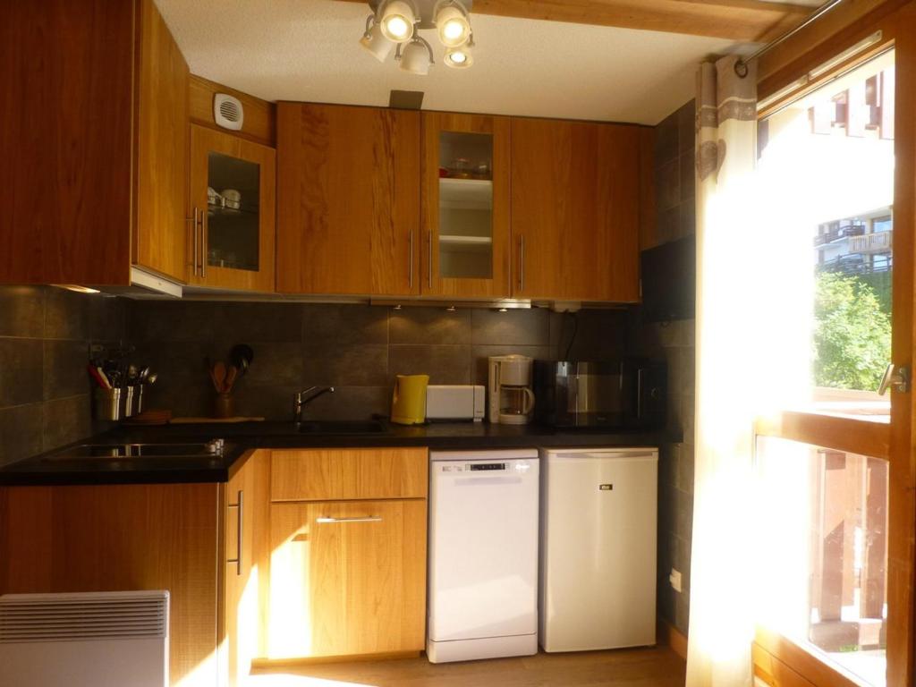 een keuken met houten kasten en een witte koelkast bij Appartement Peisey-Vallandry, 2 pièces, 6 personnes - FR-1-757-83 in Landry