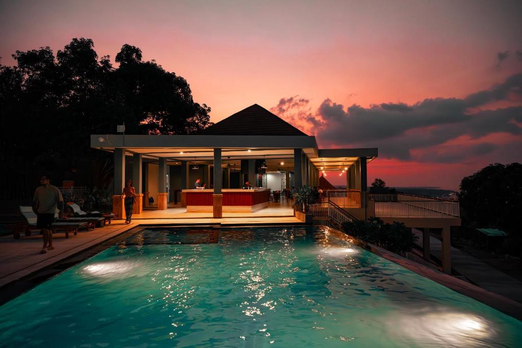 a swimming pool in front of a house at sunset at Jukung Dive Resort Bali PENIDA in Nusa Penida