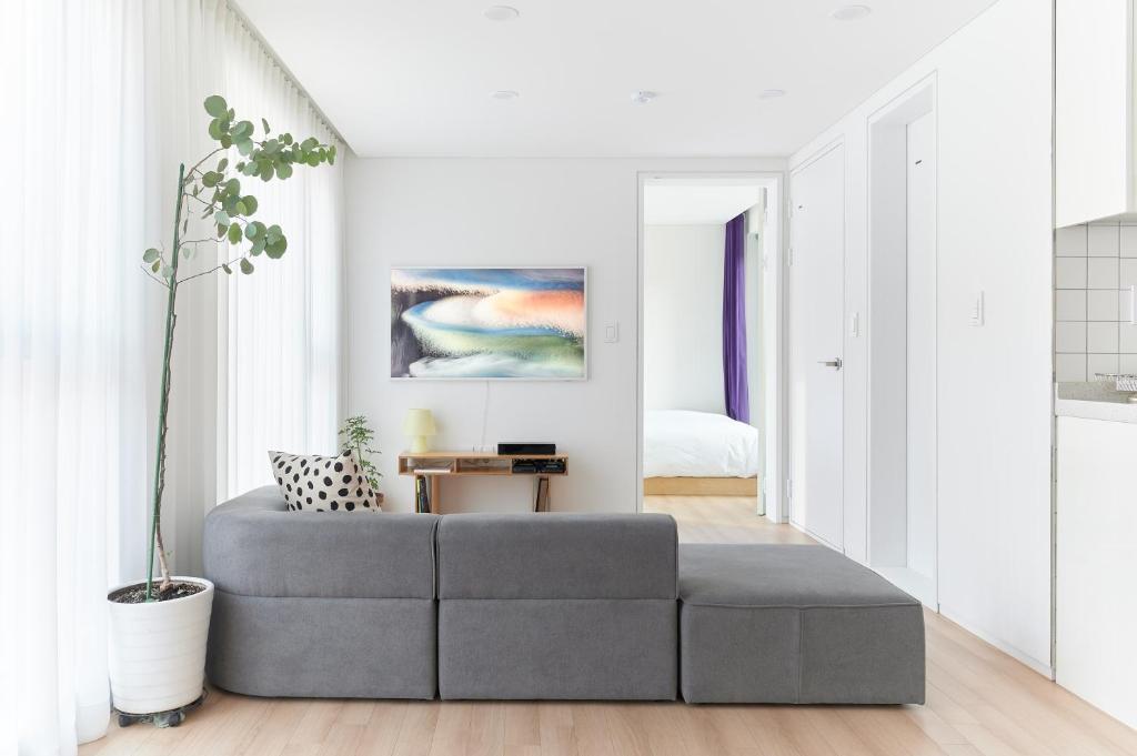 una sala de estar con un sofá gris en una habitación blanca en La Loge, en Seúl