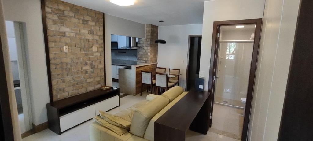 uma sala de estar com um sofá e uma parede de tijolos em The Sun Resort - Super Apartamento de 2 quartos - 1 suíte e 1 reversível em Brasília