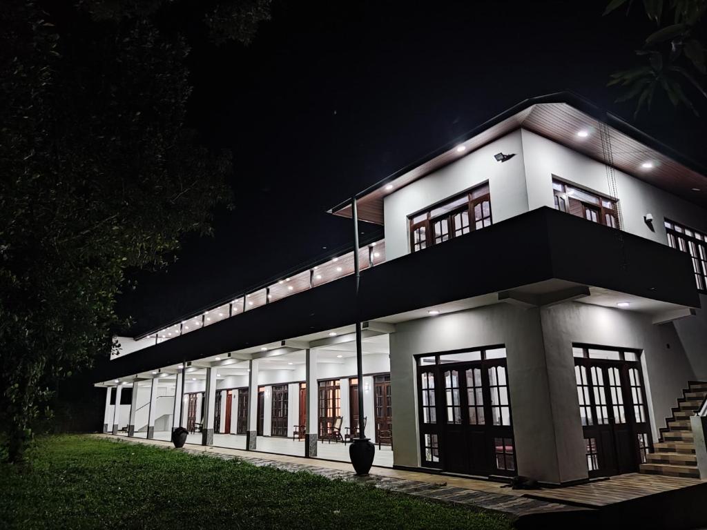 a large white building with windows at night at Victoria Nature Resort in Digana